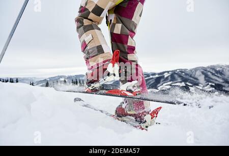 Primo piano di un'istantanea ritagliata delle gambe dello sciatore, allacciatura e sci, facendo un passo avanti, tour di sci. Vista ad angolo basso. Concetto di sport invernali Foto Stock