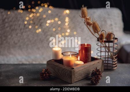 Candele nella scatola di legno isolato su sfondo grigio bianco. Luci Garland. Il concetto di atmosfera e comfort a casa, vacanze, data romantica, inverno, comfort a casa, interni, Natale o Capodanno. Foto Stock