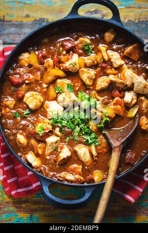 Paneer di pollo con spezie indiane. Pezzi di pollo con pepe giallo in salsa di pomodoro, prezzemolo. Foto Stock