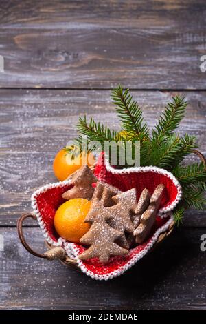 Biscotti di zenzero di avena a forma di albero di Natale cosparsi di zucchero in polvere con mandarini in un cestino su un tavolo di legno, stile rustico, Foto Stock