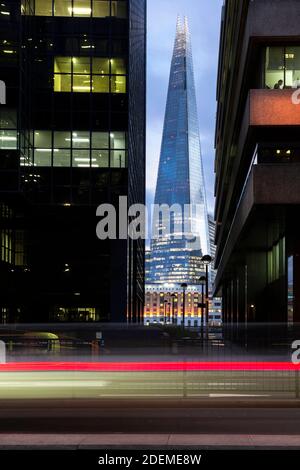 Vista della Shard tra i blocchi di torre illuminati al crepuscolo, come visto da Lower Thames Street, Londra, marzo 2020 Foto Stock