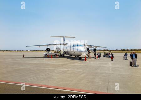 I passeggeri che sbarcano da un Airlink sudafricano Avro RJ85 sulla pista all'arrivo su un volo regionale, l'aeroporto di Maun, il Botswana, l'Africa meridionale Foto Stock