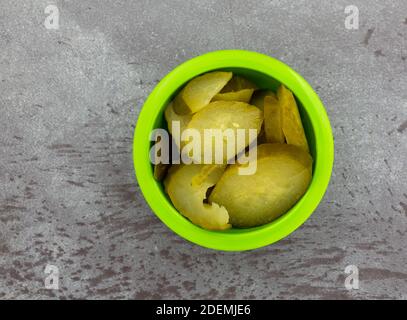 Vista dall'alto di una piccola ciotola verde piena di insalata di cetrioli su uno sfondo grigio. Foto Stock