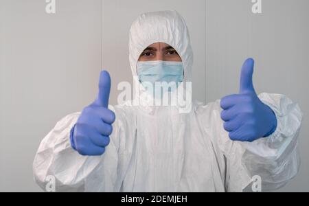 Primo piano di un'infermiera in una tuta protettiva che fa un gesto con le mani. Pandemia di coronavirus, covid 19. Operaio sanitario all'interno di un ospedale WIT Foto Stock