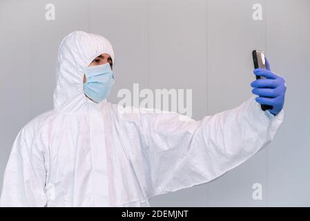 Infermiere di sesso maschile che parla con il paziente che parla sul telefono cellulare all'interno della configurazione clinica in mezzo a pandemia di Coronavirus. Concetto di telemedicina con smartphone Foto Stock