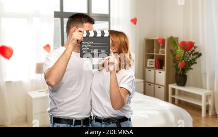 felice coppia in t-shirt bianca con clapperboard Foto Stock