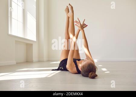 Donna snella che pratica ginnastica ritmica o danza in uno studio luminoso. Foto Stock