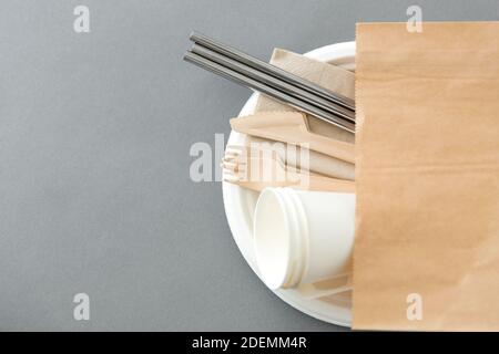 forcelle di legno, coltelli e tazze di carta sulla piastra Foto Stock