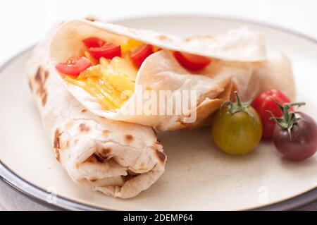 prima colazione burrito con formaggio, uova e pomodori ciliegini al telaio Foto Stock