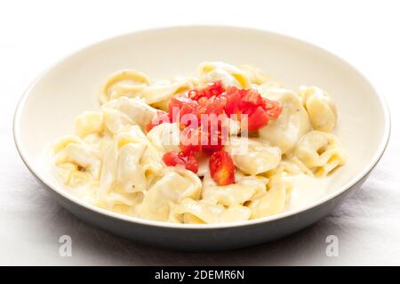 Cremosa salsa Alfredo con pollo tortelli ripieni e rabboccato con fresco cubettato di pomodoro Foto Stock