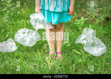 Usato sacchetto di plastica vuoto nelle mani di una bambina durante la pulizia del parco da detriti Foto Stock