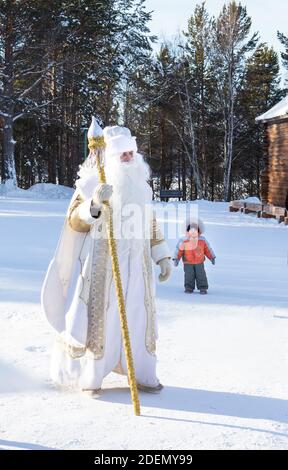 Irkutsk, Russia - 8 gennaio 2019: Padre Frost si è svegliato nel parco del museo etnografico Taltci. Bambino piccolo che guarda l'uomo alto. Foto Stock