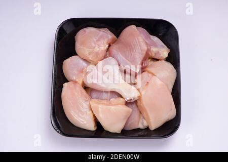 Pollo crudo tenero curry tagliato senza pelle disposto su nero sfondo di colore bianco Foto Stock