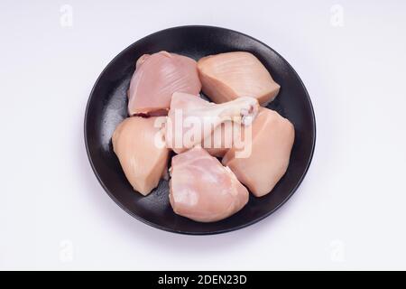 Pollo crudo tenero curry tagliato senza pelle disposto su nero piastra con sfondo bianco testurizzato Foto Stock