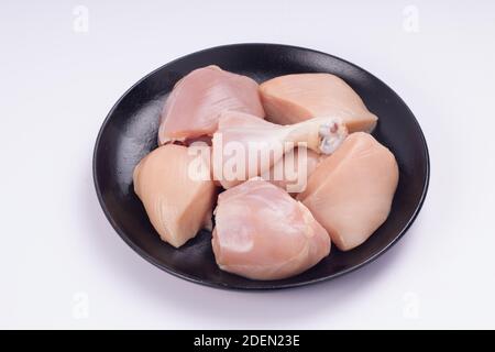 Pollo crudo tenero curry tagliato senza pelle disposto su nero piastra con sfondo bianco testurizzato Foto Stock