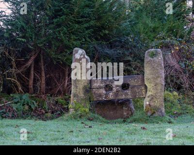 Stocks di punizione di pietra e legno nel villaggio inglese, Devon. Foto Stock