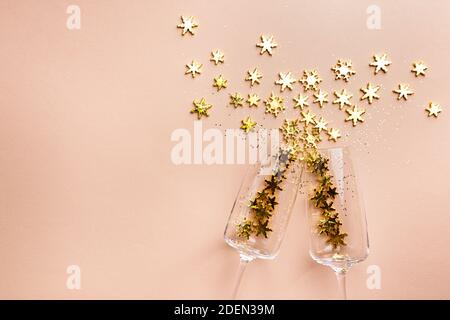 Bicchieri di champagne con spruzzi dorati scintillanti su sfondo rosa. Disposizione piatta, vista dall'alto, stile natalizio alla moda. Foto Stock