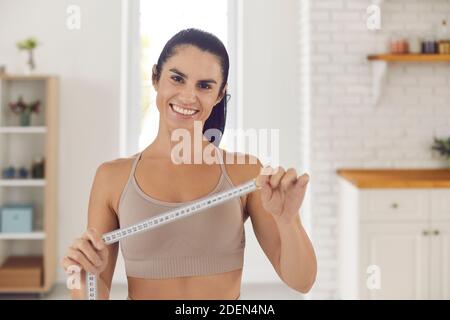 Perdita di peso allenatore che tiene metro a nastro, sorridente e motivante a rendere il vostro corpo perfetto Foto Stock