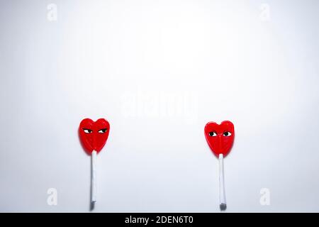 Piano Cenitale. Due lollipop a forma di cuore separati l'uno dall'altro. Concetto di San Valentino durante la pandemia e la distanza di sicurezza del Covid-19 Foto Stock
