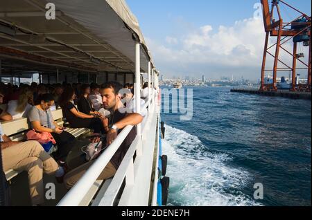 Istanbul, Turchia - Settembre, 2018: Persone che viaggiano in traghetto pubblico da Kadikoy in Bosforo. I giovani seduti all'interno del traghetto ascoltano la musica Foto Stock