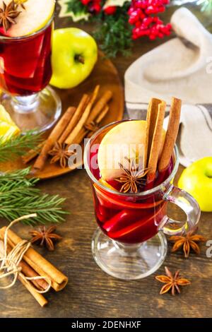 Inverno bevanda calda natalizia con arancia, mela e spezie. VIN brulé in tazza di vetro con spezie su tavola rustica. Foto Stock