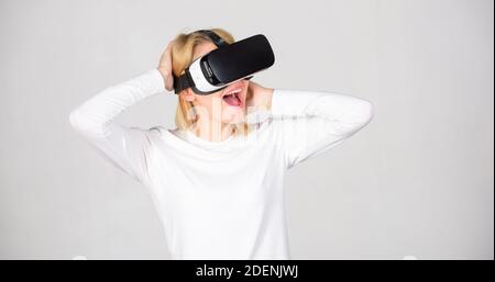 Stupiti giovane donna toccando l'aria durante l'esperienza di VR. Una persona in bicchieri virtuale mosche di spazio in camera. Donna eccitato usando 3d occhiali protettivi. Digital VR Foto Stock