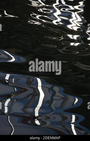 I riflessi creano modelli astratti nell'acqua di un oceano porto Foto Stock