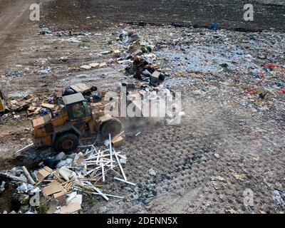 Vista dall'alto del drone della discarica. Diversi tipi di rifiuti in discarica della grande città. Il trattore trasporta rifiuti. Foto Stock