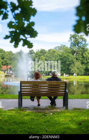 Coppia matura irriconoscibile seduta sulla panchina vicino allo stagno Foto Stock