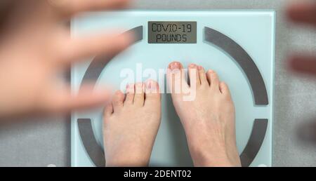 Piedi in piedi su scala di peso digitale con le parole COVID-19 libbre scritte su, coronavirus e concetto di dieta. Vista dall'alto Foto Stock