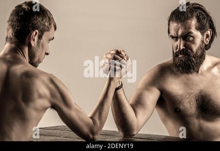 Armi che lottano mano sottile, grande braccio forte in studio. Due mani di uomo hanno stretto il braccio wrestling, forte e debole, corrispondenza disuguale. Uomo pesantemente muscled bearded Foto Stock