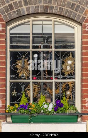 una finestra di periodo con finestre di frassino decorate con decorazioni natalizie per il stagione festiva Foto Stock