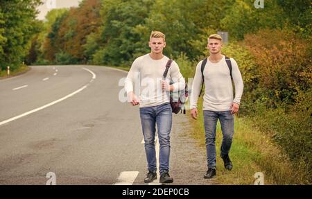 Amici hitchescursionisti in viaggio. Inizia la grande avventura nella tua vita con hitchhiking. Compagnia amici viaggiatori hitchtrekking a sfondo natura strada. Foto Stock