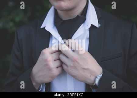 Un primo piano di uno sposo che fissa i pulsanti sul camicia Foto Stock