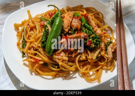 Pad kee mao altrimenti noto come noodles ubriachi è un Piatto di noodle thai piccante fritto in padella con cosce di pollo a fette sottili e broccoli cinesi Foto Stock