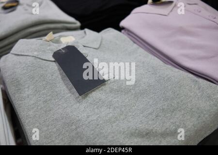 T-shirt bianche multicolore con colletto e etichette al banco del negozio Foto Stock