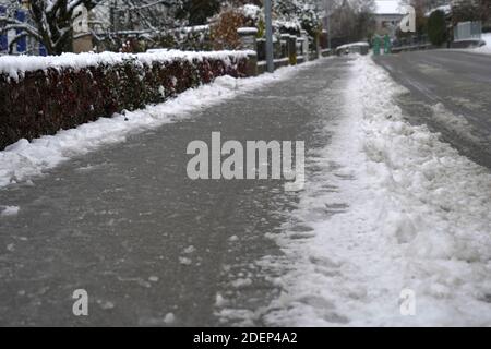 Marciapiede e strada di un villaggio in Svizzera in inverno. La neve è trattata con sale stradale per rendere la strada meno scivolosa e garantire la sicurezza. Foto Stock