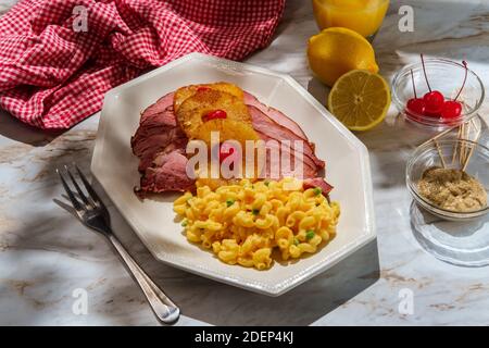 Cena al prosciutto di agrumi smaltato al miele arrosto con anelli di ananas a fette e le ciliegie di maraschino servite con un lato di pisello verde maccheroni e formaggio Foto Stock