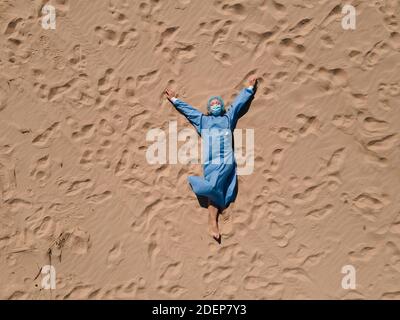 Set divertente: Stanco medico in attrezzatura medica sdraiato sulla spiaggia di sabbia Foto Stock