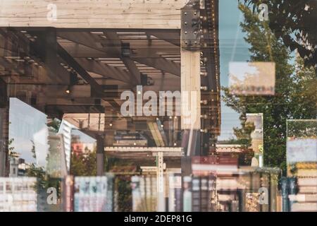 Librerie offuscate di librerie con libri colorati, riflessi di strade di strade della città in vetrina di vetro. Lettura e vendita di libri, abs Foto Stock