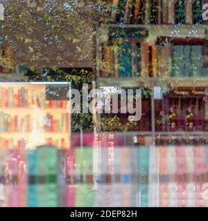 Astratto sfondo quadrato offuscato con riflessi di librerie con libri colorati e vista sulla città, doppia esposizione Foto Stock