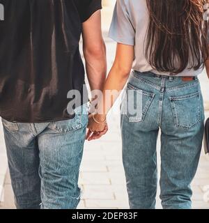 Tenendo le mani da vicino di una coppia irriconoscibile da dietro, romantica passeggiata congiunta Foto Stock