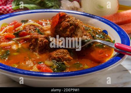 Zuppa di polpette di pomodoro con fagioli cannellini verdino di spinaci piselli e scorza di parmigiano Foto Stock