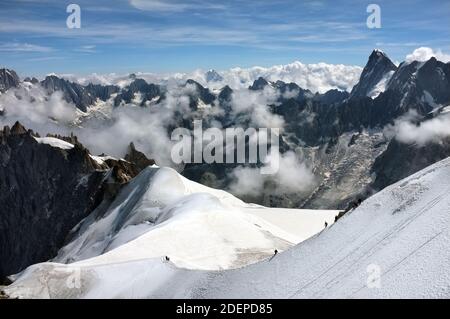 Gli scalatori sul ghiacciaio del Monte Bianco appaiono poco più che puntini neri contro la neve bianca e il maestoso Sfondo della montagna più alta d'Europa Foto Stock