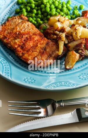 Porkchops grigliati marinati in glassa di miele con patatine fritte fatte in casa e piselli verdi Foto Stock