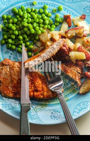 Porkchops grigliati marinati in glassa di miele con patatine fritte fatte in casa e piselli verdi Foto Stock