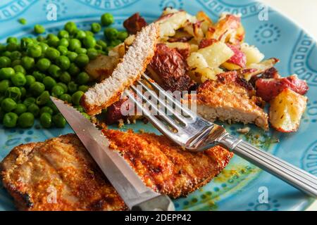 Porkchops grigliati marinati in glassa di miele con patatine fritte fatte in casa e piselli verdi Foto Stock