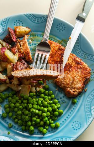 Porkchops grigliati marinati in glassa di miele con patatine fritte fatte in casa e piselli verdi Foto Stock