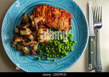 Porkchops grigliati marinati in glassa di miele con patatine fritte fatte in casa e piselli verdi Foto Stock