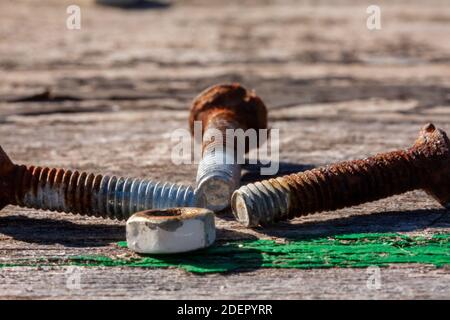 Vecchio dado arrugginito e viti su un vecchio tavolo di legno. Foto Stock